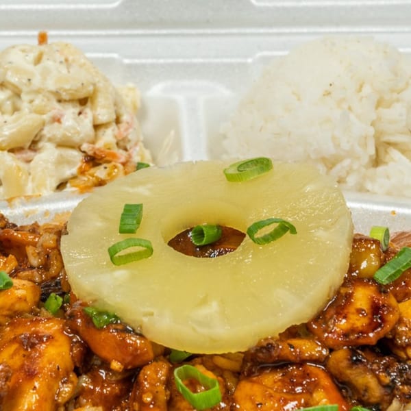 Hawaiian teriyaki chicken with pineapple, rice, and macaroni salad in a white takeout container.